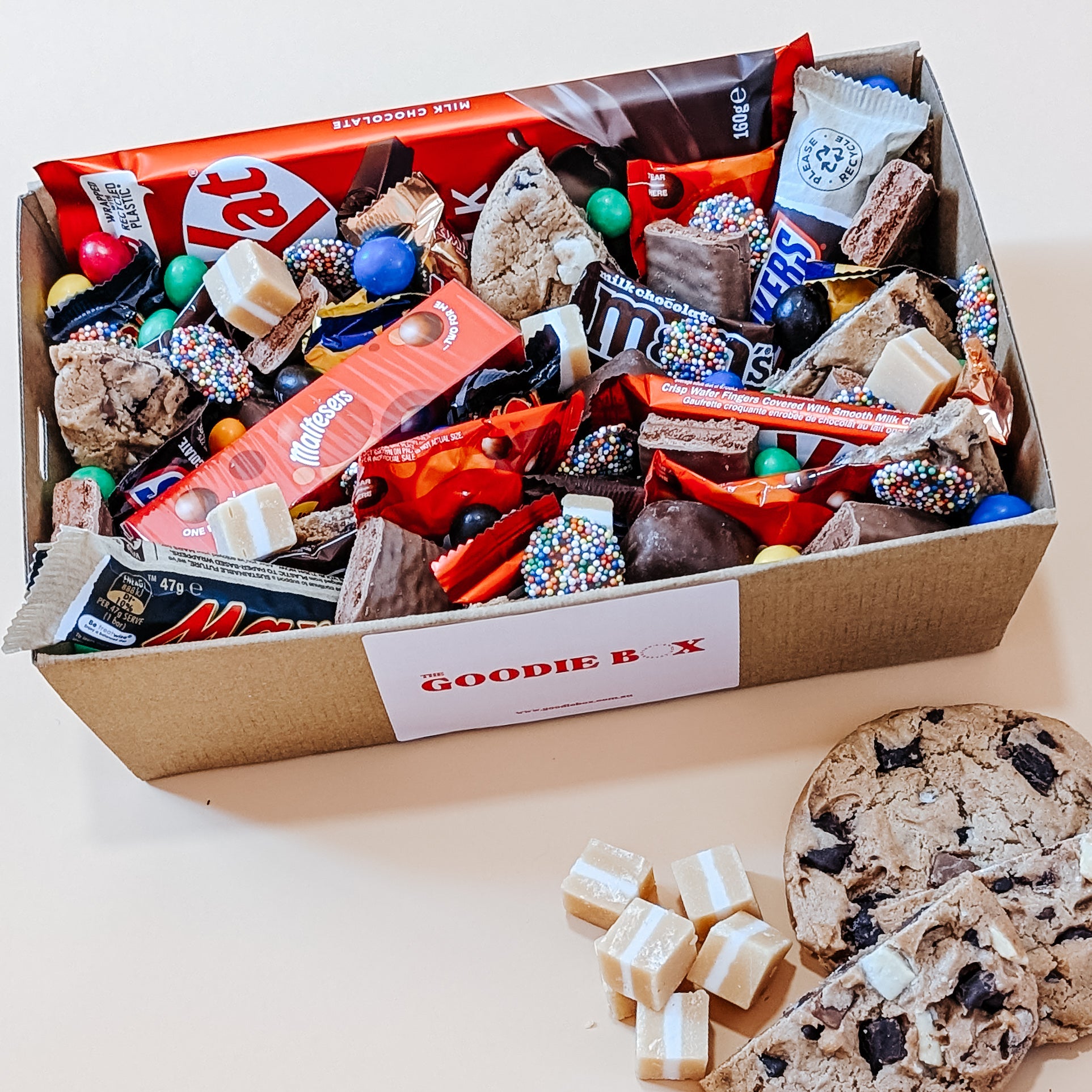 Photograph of a chocolate dessert box featuring an assortment of treats including Kit Kat, Maltesers, Twix, M&M's, and creamy fudge.