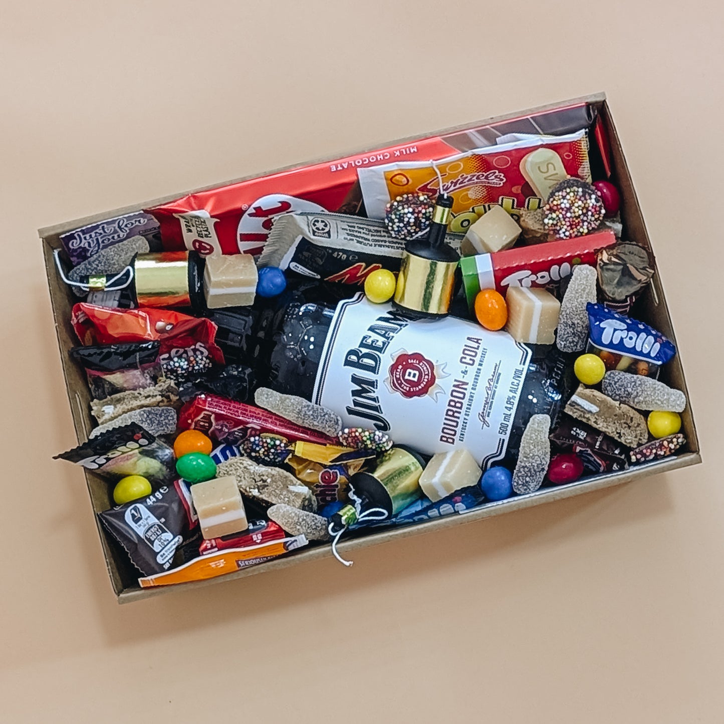 Photograph of gift hamper that includes Jim Beam Bourbon, cookies, tim tams, trolli lollies, whizz fizz and more.