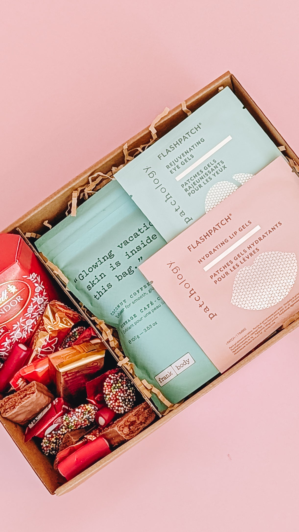 Photograph of pamper hamper. The box is filled with pampering goods such as Frank Body scrub, eye mask and lip mask and contains an assortment of sweet treats.