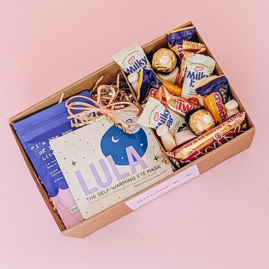 Photograph of pamper hamper sleepy time filled with gold hair claw, frank body scrub, Lula self warming eye mask and a selection of sweet treats, including marshmallows, Crunchie, Milky Bar, Twix & Ferrero Rocher.