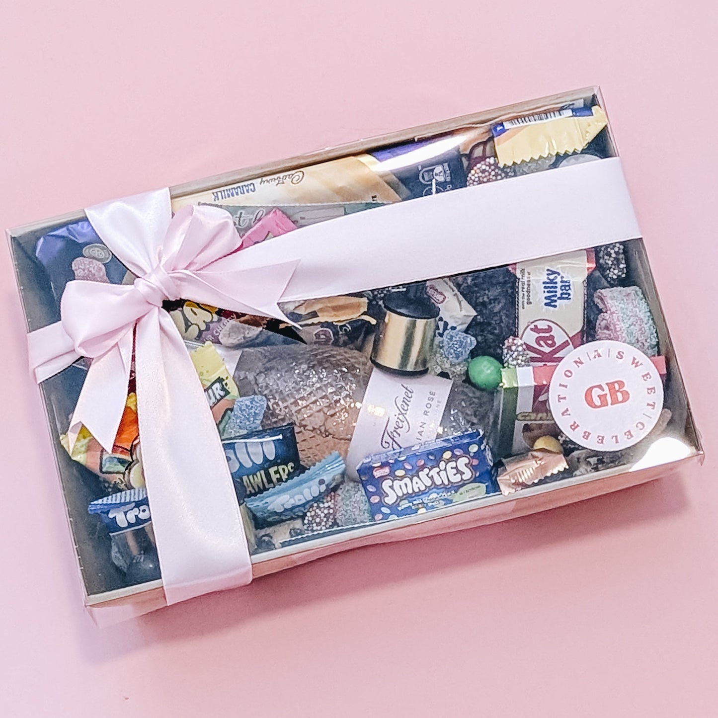 Photograph of dessert birthday box for her featuring sparkling wine, party poppers, chocolates, cookies and lollies.