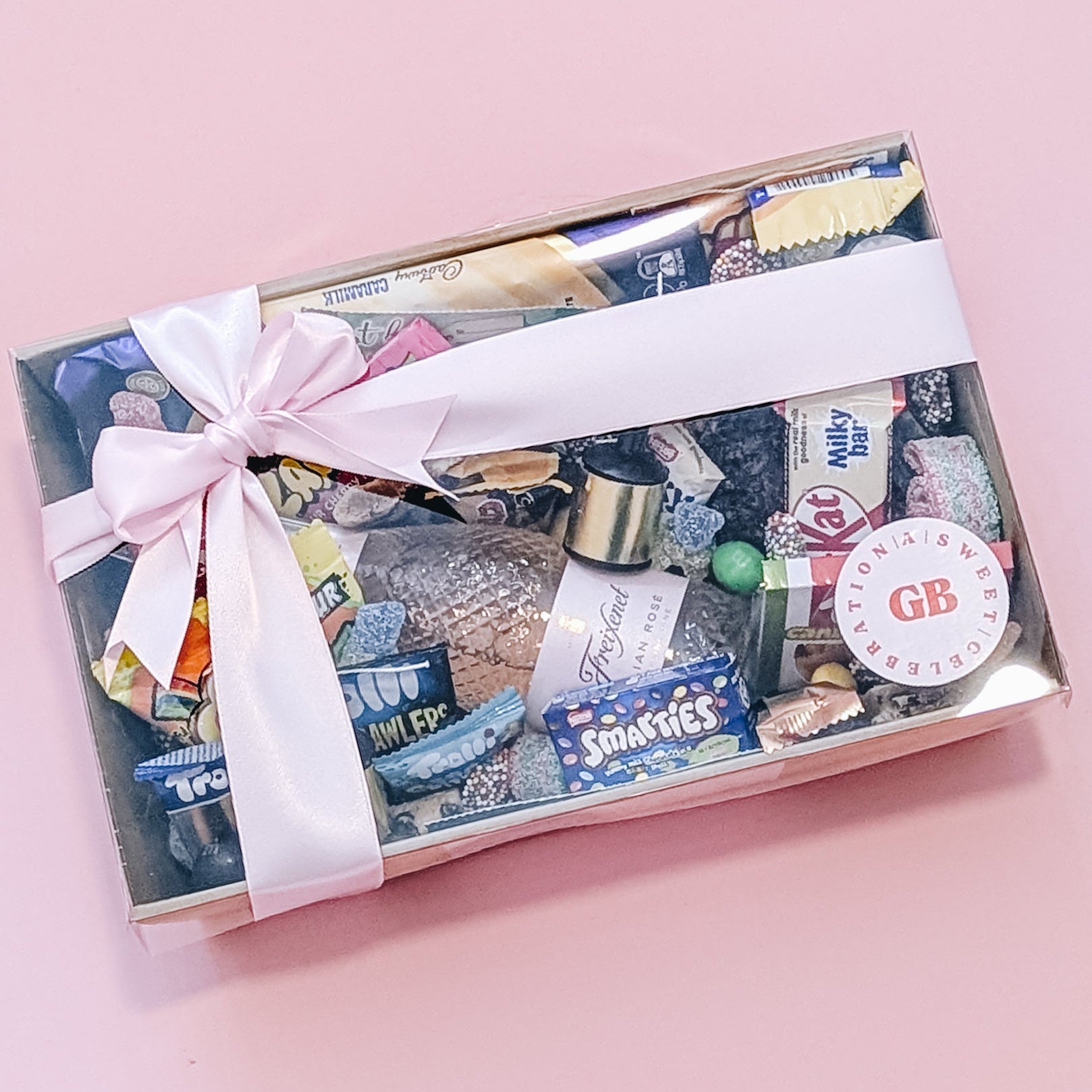 Photograph of dessert birthday box for her featuring sparkling wine, party poppers, chocolates, cookies and lollies.