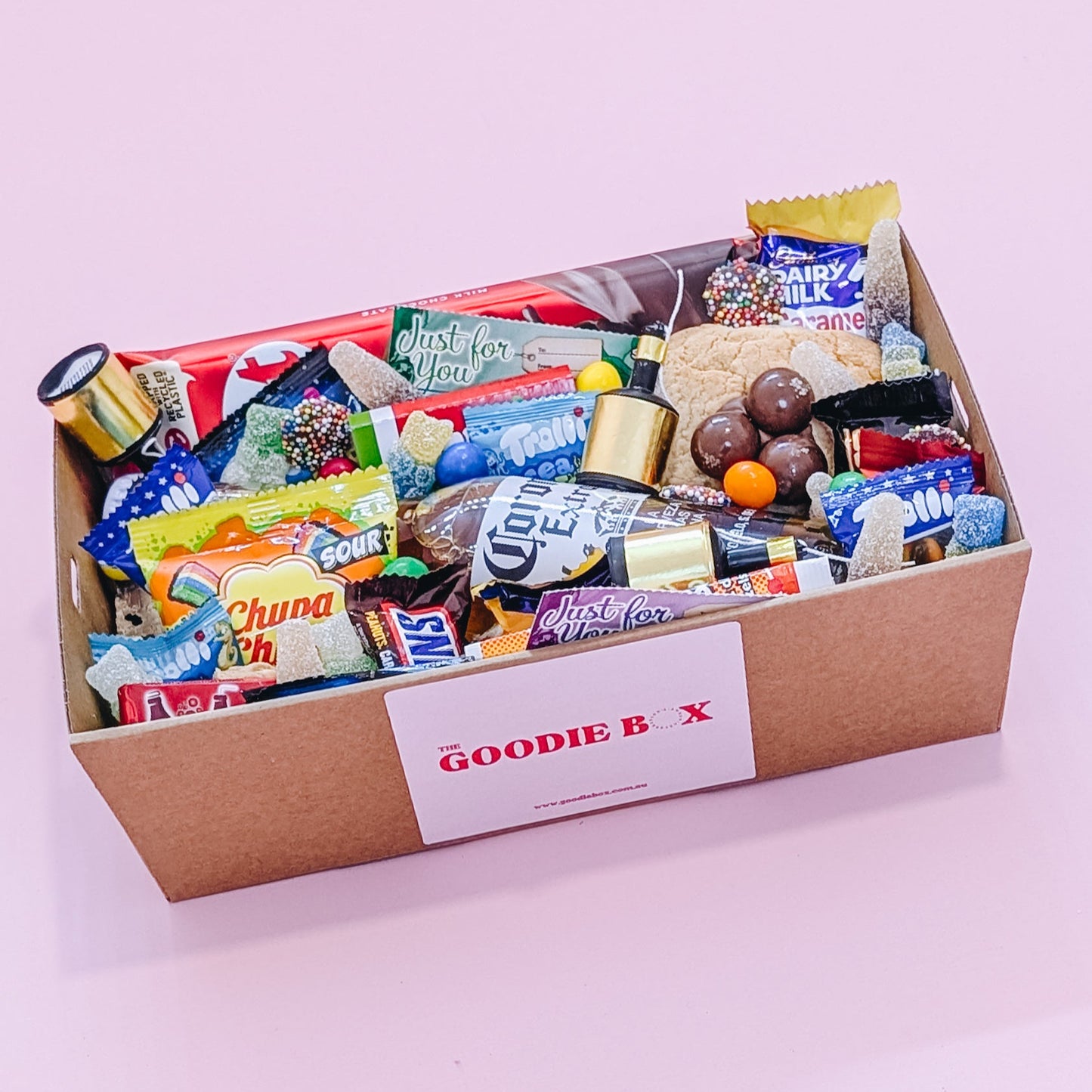 Photograph of gift box filled with Corona, Nerds, Cadbury Dairy Milk, Trolli Lollies and an assortment of mini chocolates and loose cookies and sweets.
