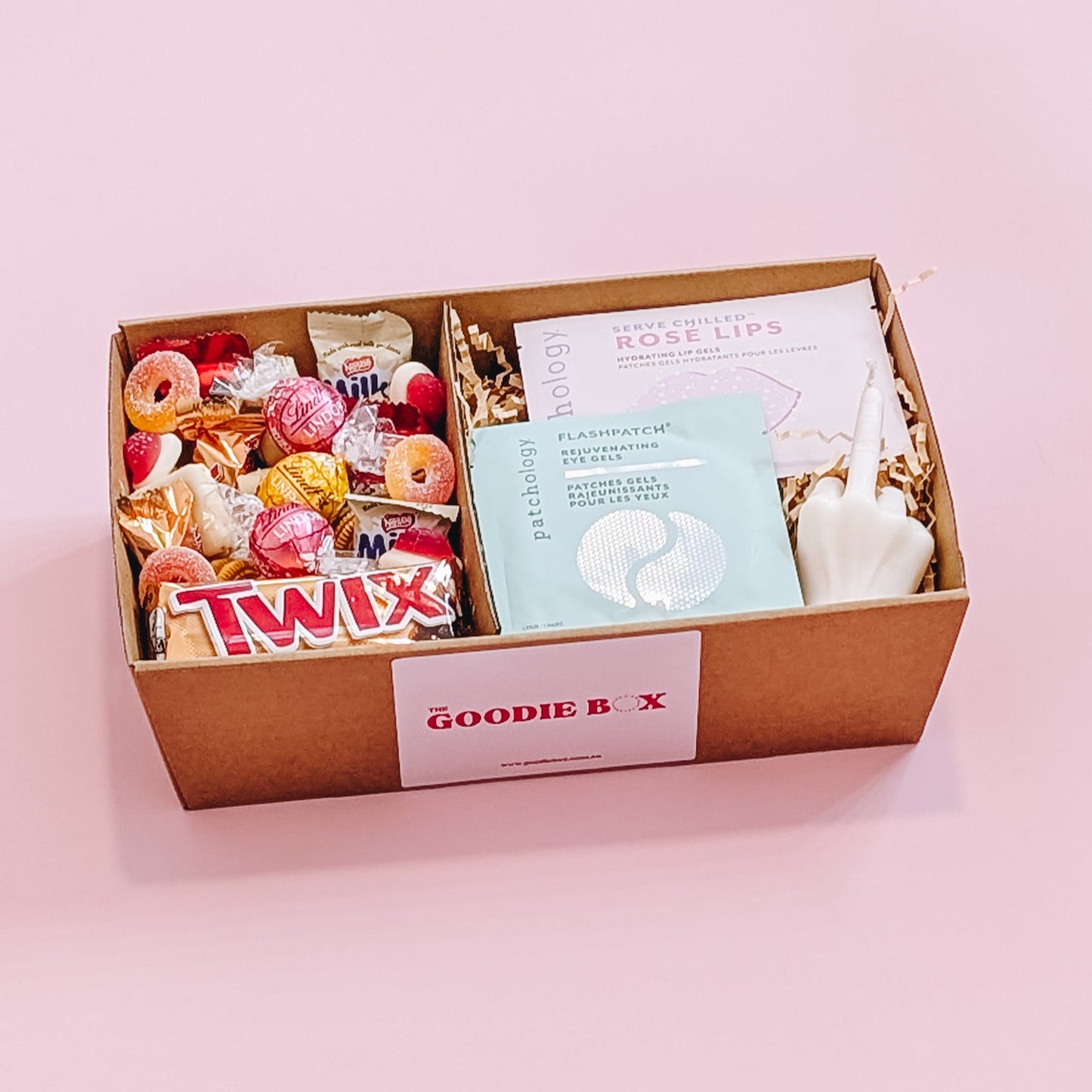 Photograph of the better off without him gift pamper hamper. The gift box is filled with a patchology eye and lip mask, a rude finger candle and an assortment of chocolate, lollies, and cookies.