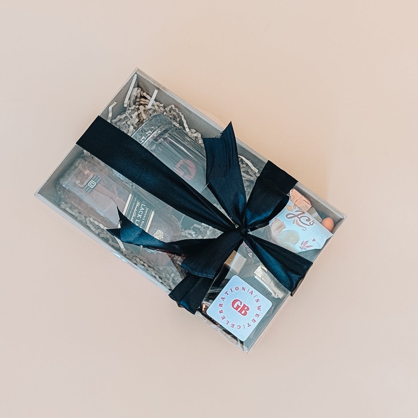 Photograph of whisky gift set for him. The gift set is wrapped in a black satin bow.