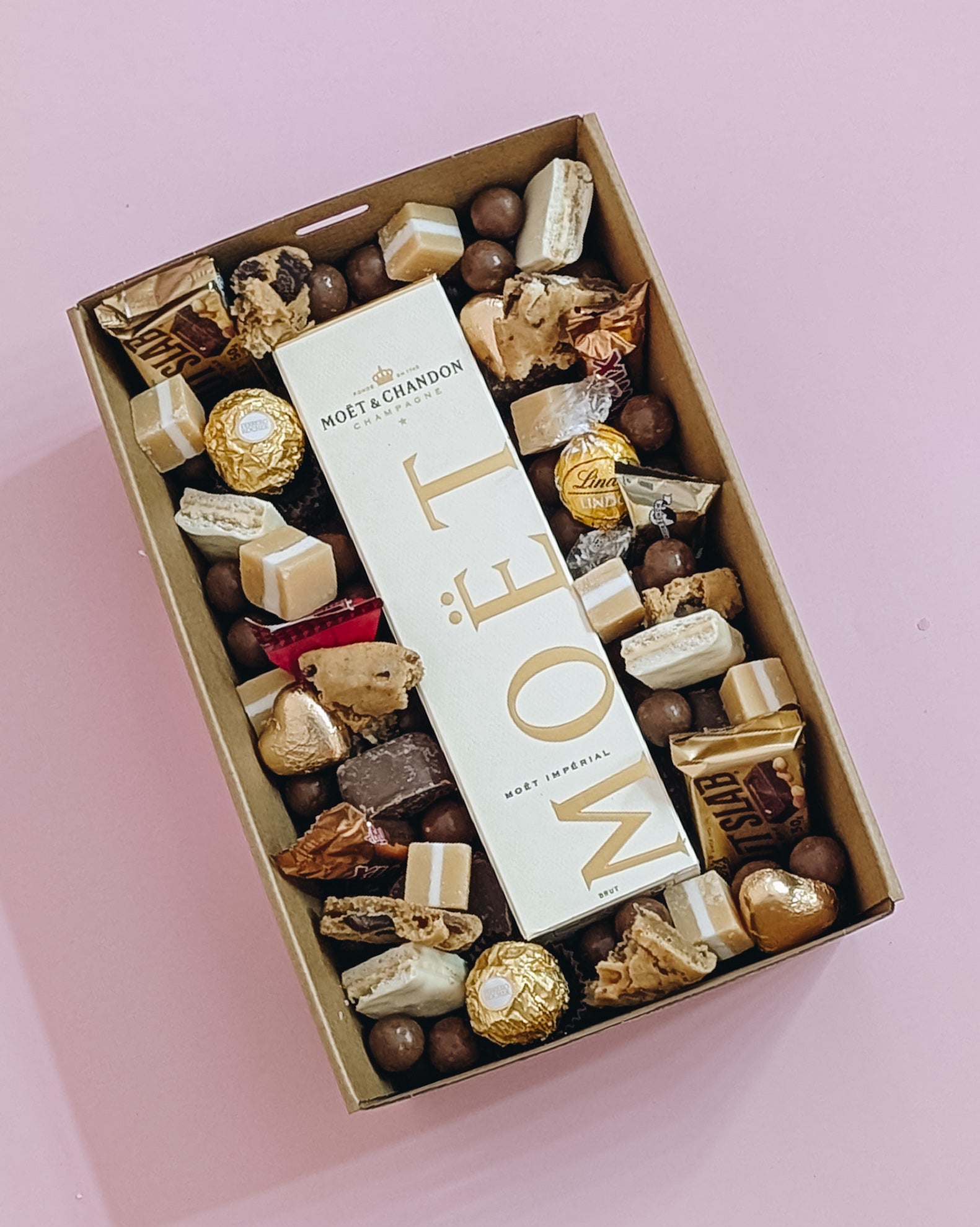 Photograph of Luxury Moët Champagne and chocolate gift hamper with personalized message. Wrapped with a beautiful gold bow ready for gifting.