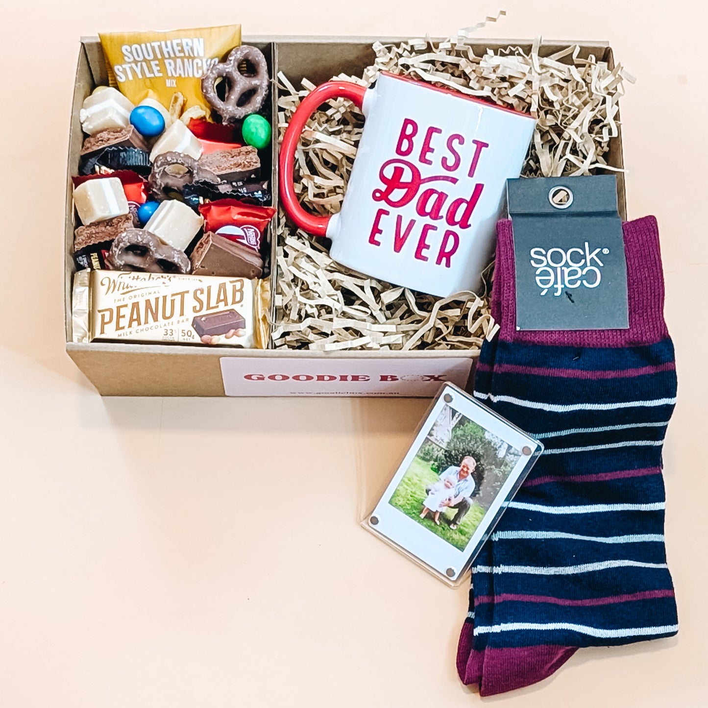 Fathers Day gift hamper with snacks, mug, magnetic photo with frame and socks on a light background