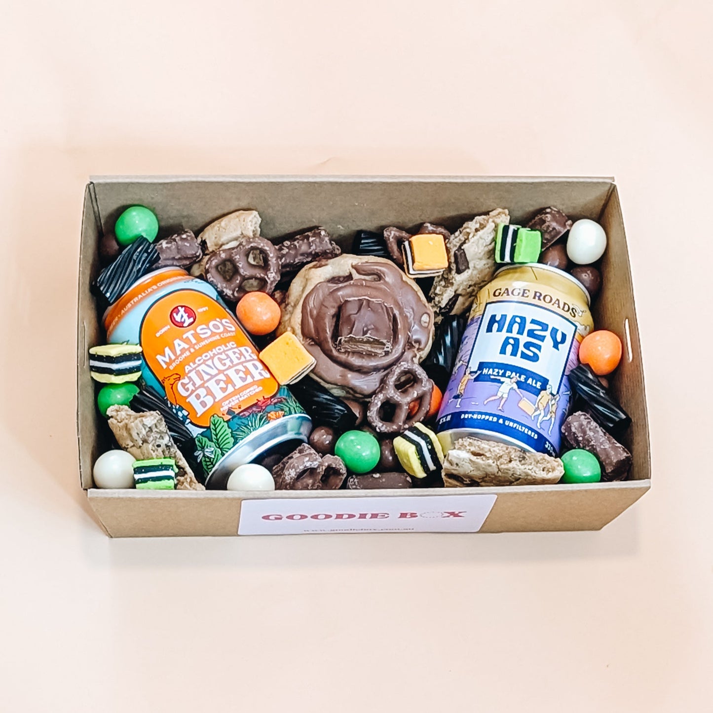 Fathers day box of assorted snacks including cookies, chocolates, and craft beer on a beige background