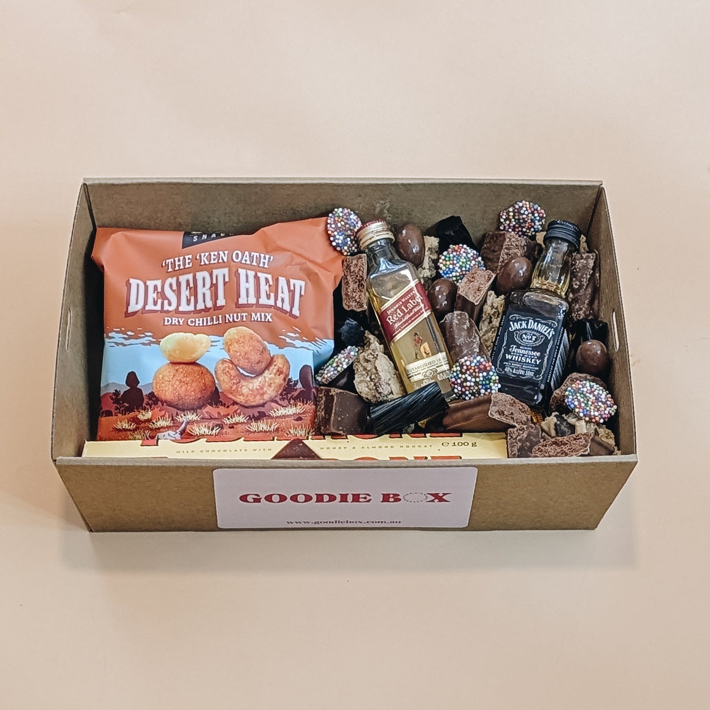 Fathers Day gift box of snacks and whisky with a Goodie Box label on a beige background