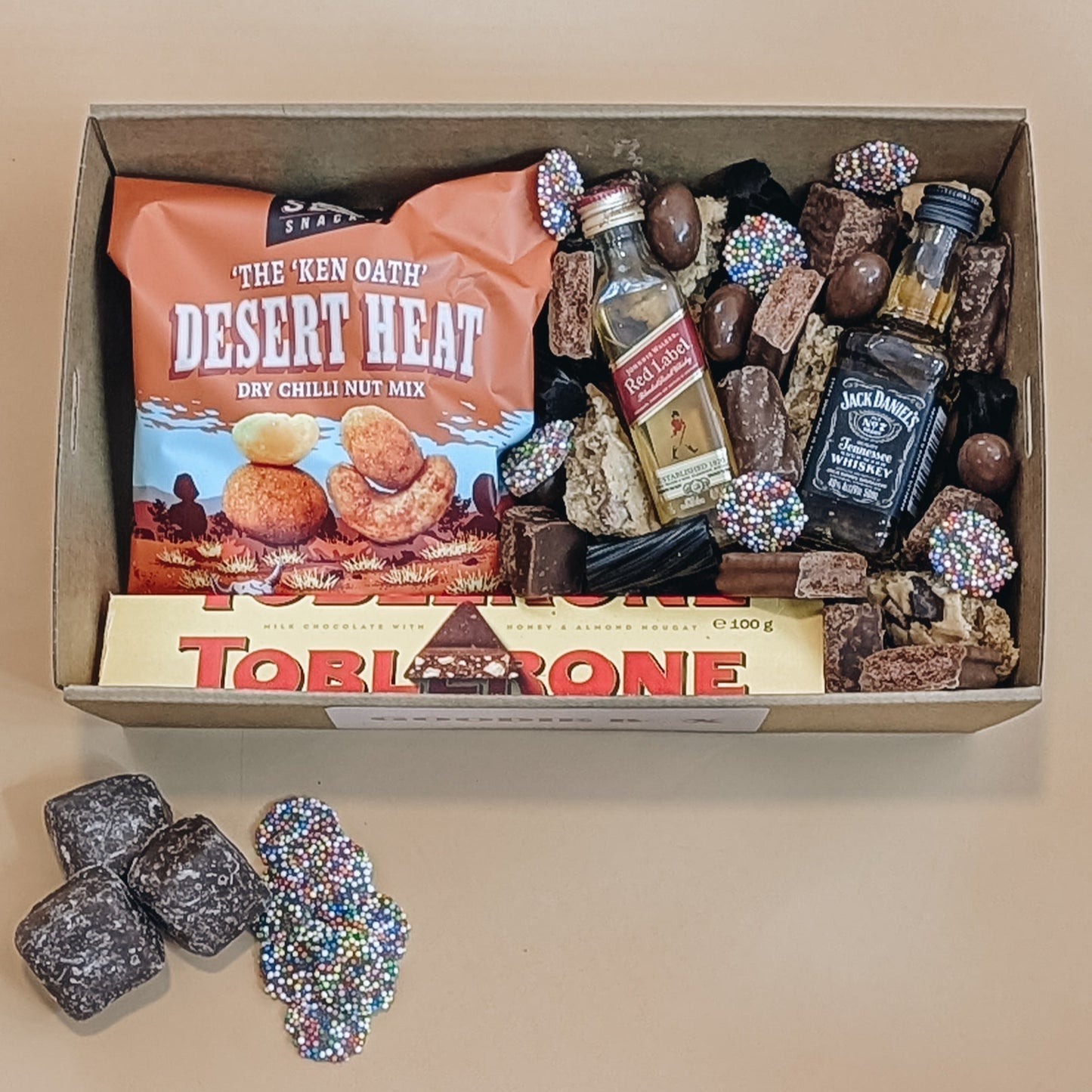 Fathers day gift box with nuts, chocolate, and whiskey on a beige background