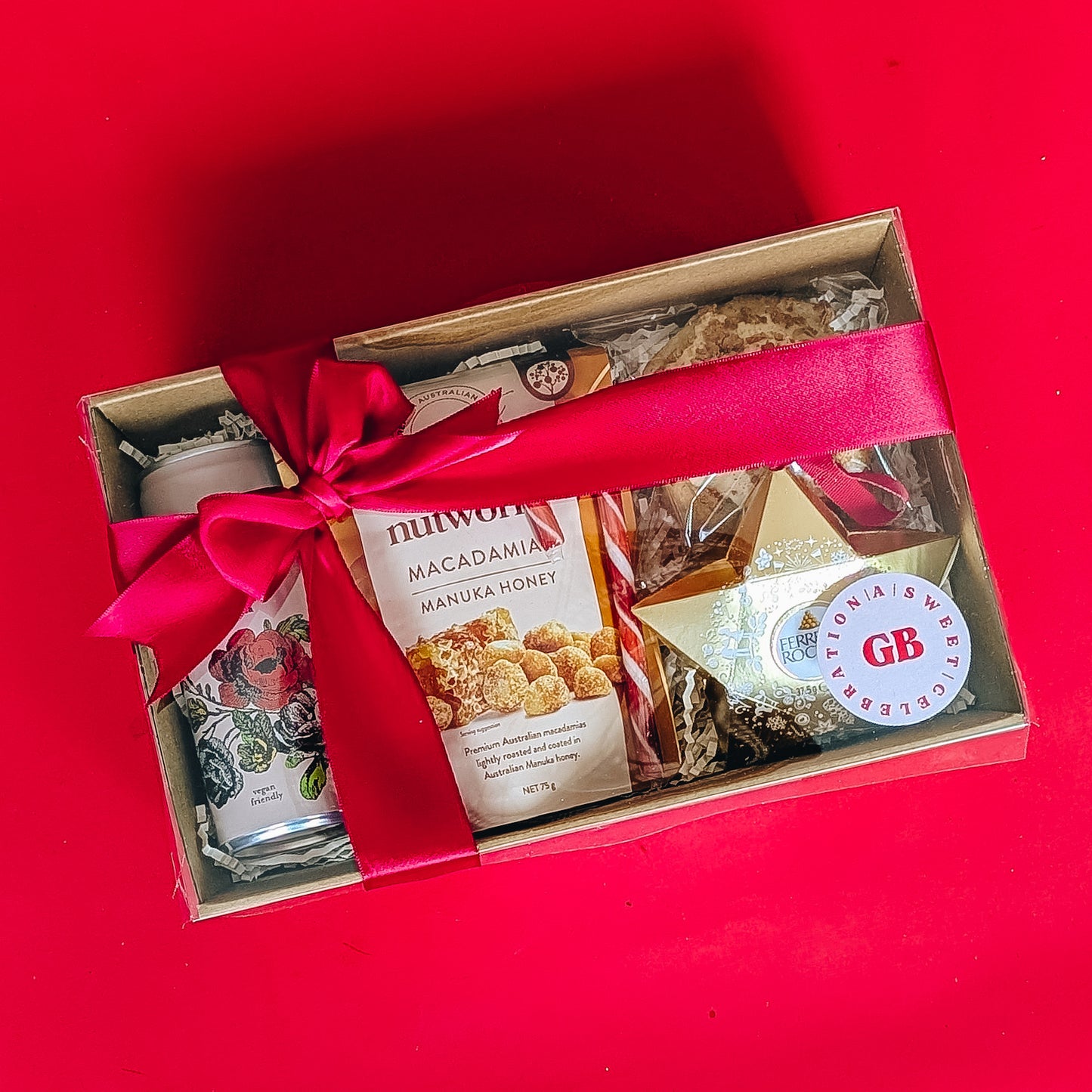 Gift box with snacks and a red ribbon on a red background