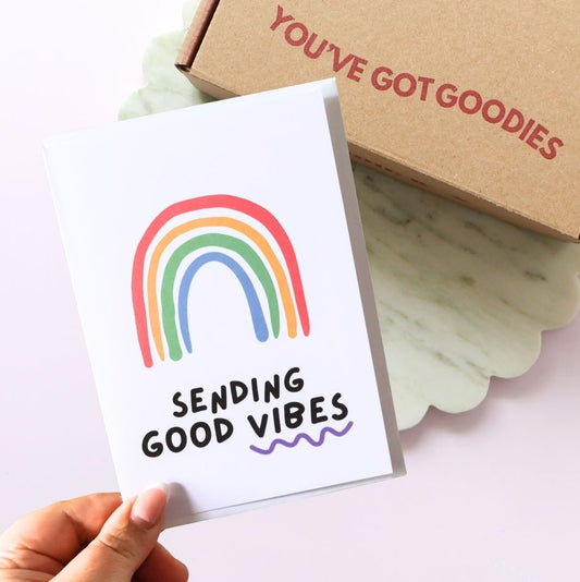 sending good vibes greeting card with a colourful rainbow drawing. A gift box in the background reading you've got goodies