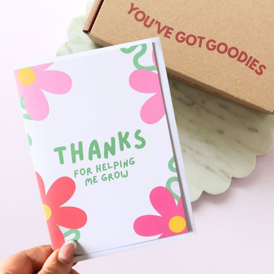 Floral card with 'THANKS FOR HELPING ME GROW' text held by a hand, with a box labeled 'YOU'VE GOT GOODIES' in the background.
