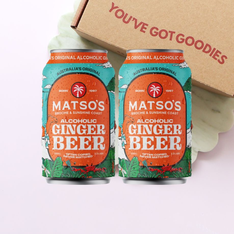 Two cans of Matso's Alcoholic Ginger Beer with a cardboard box in the background.