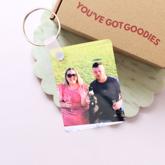 Keychain with a photo of two people and a box labeled 'You've Got Goodies' on a light background