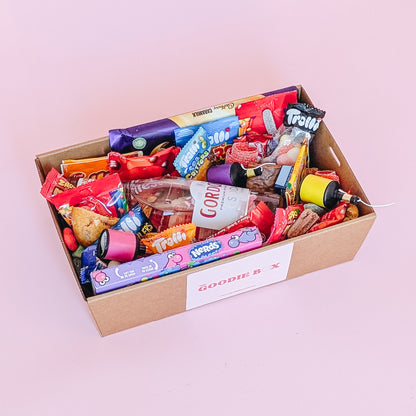 Photograph of gift box filled with Gordon's pink gin, Nerds, Cadbury CaraMilk, Trolli Lollies and an assortment of mini chocolates and loose cookies and sweets. 