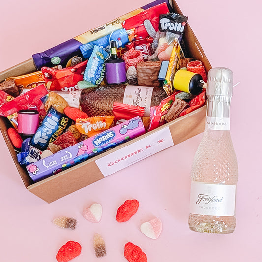 Photograph of dessert birthday box for her featuring sparkling wine, party poppers, chocolates, cookies and lollies. 