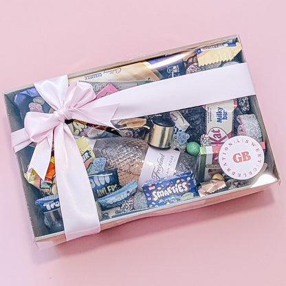 Photograph of dessert birthday box for her featuring sparkling wine, party poppers, chocolates, cookies and lollies.