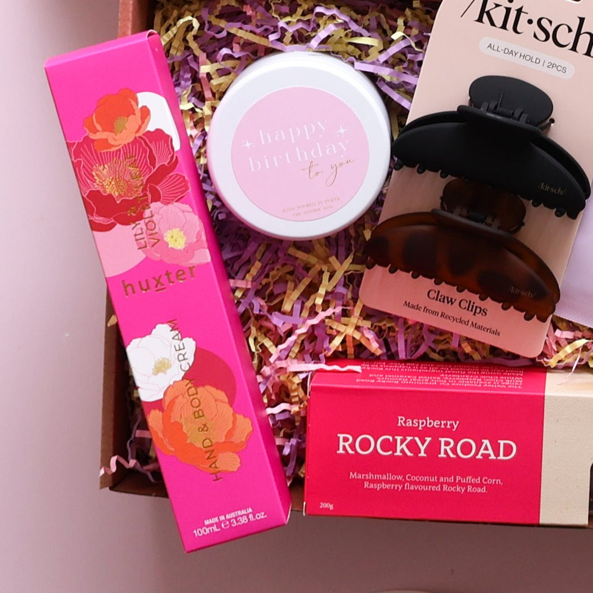 Close up of birthday gift box for her with Happy Birthday candle, Lily & Violet hand cream, claw clips and rocky road