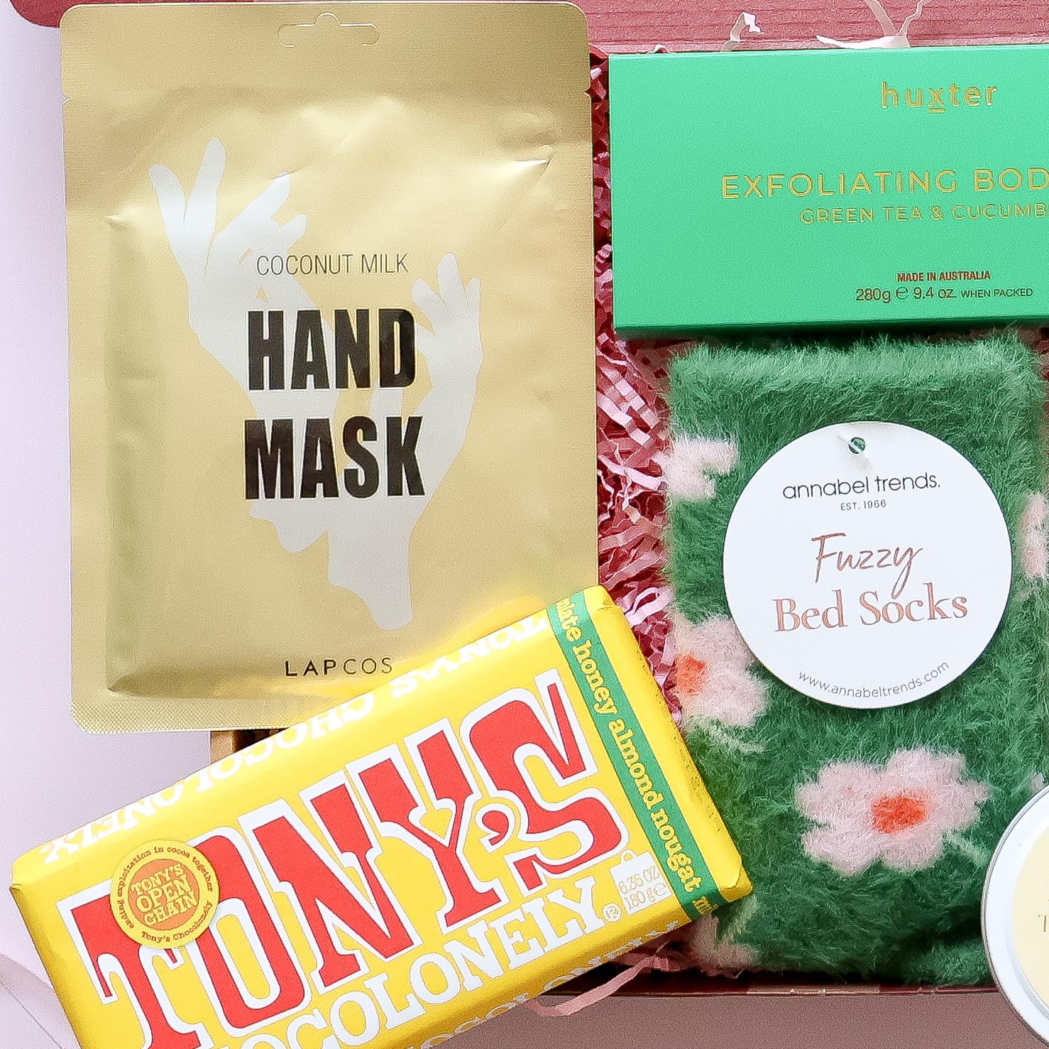 Pamper gift box detail showing Lapcos hand mask Tony's Chocolonely and Huxter green tea cucumber body bar 