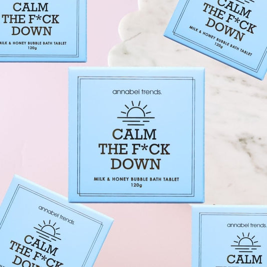 Bath tablet packaging with text 'Calm The F*ck Down' by annabel trends on a marble background.