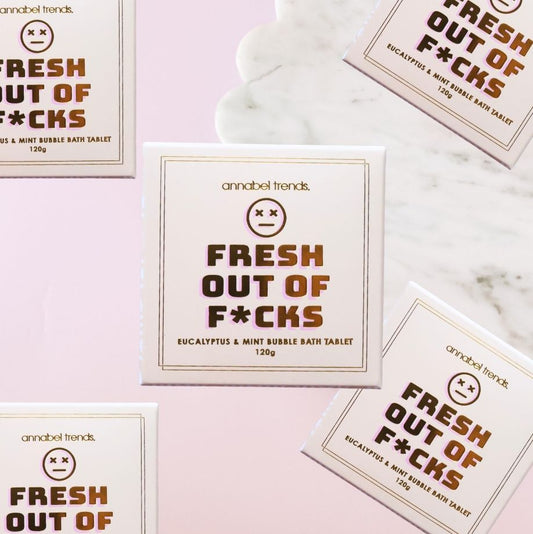 Bath tablet packaging with 'Fresh Out of F*cks' text on a marble surface.