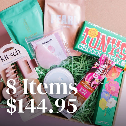 Collection of beauty and lifestyle products including a box of Tony's Chocolonely, Kit-sch hair clips, and other items on a pink background.