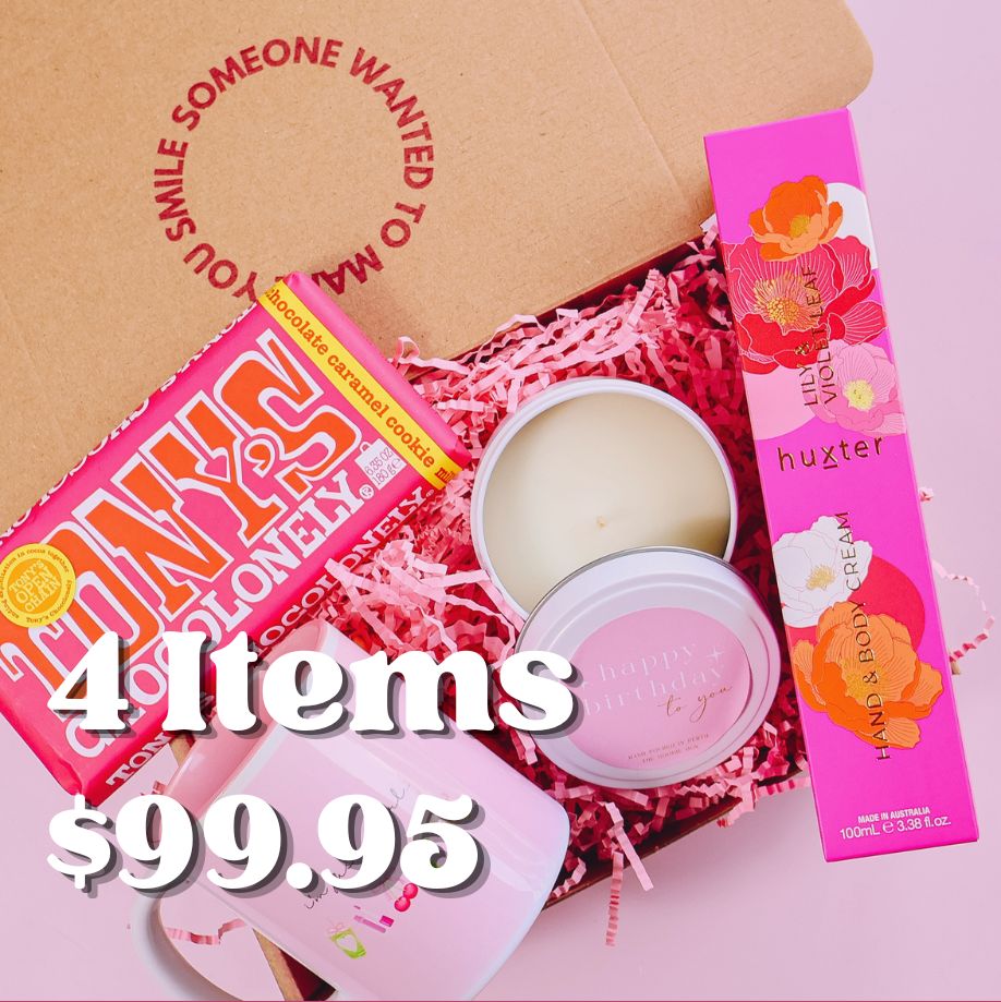 open gift box displaying items including a candle a Huxter hand and body cream, a pink mug and block of Tony's Chocolonely chocolate in a box with pink shredded paper and gift box reading "someone wanted to make you smile".