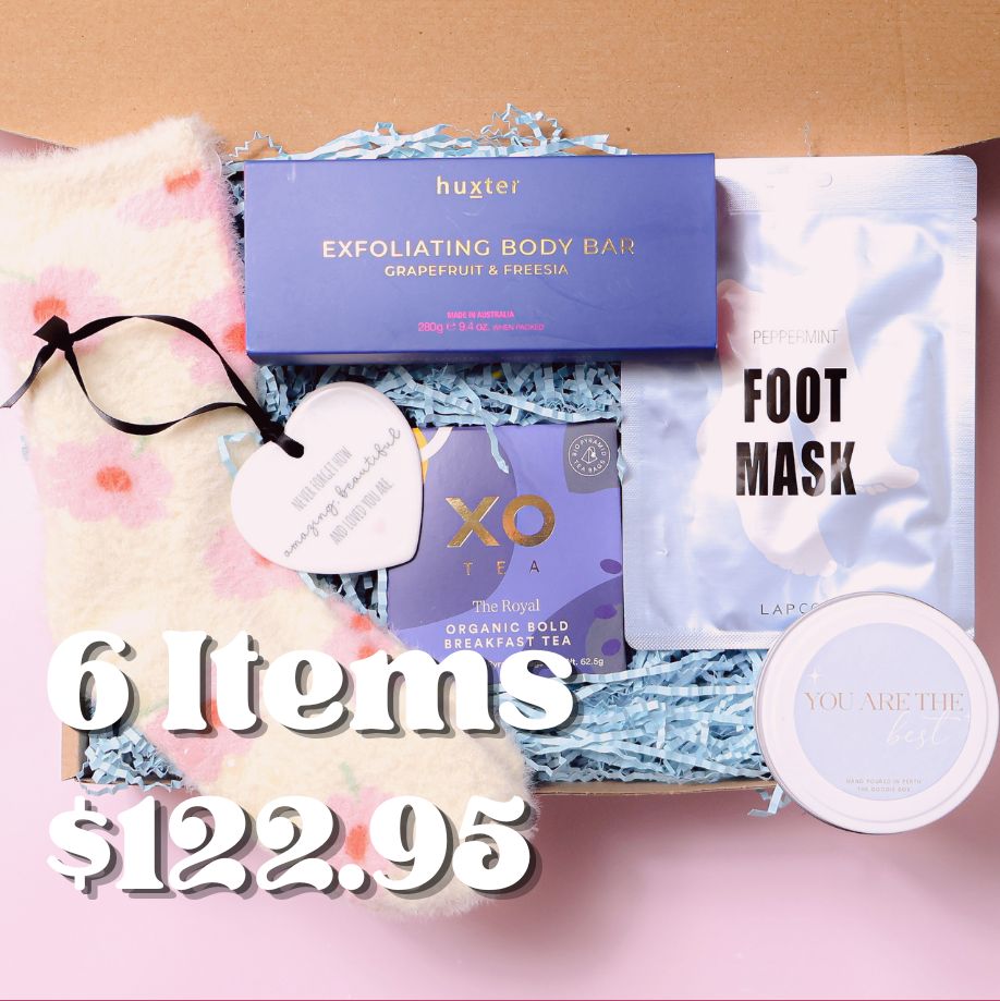 Gift box with fluffy bed socks, foot mask, XO tea, Scented candle reading "you are the best", exfoliating body bar and a ceramic keepsake ornament on a pink background.