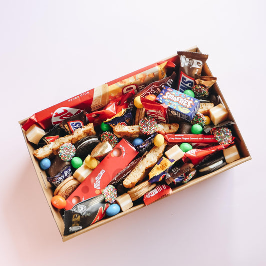 Goodie Box chocolate lovers dessert box overhead flatlay packed with KitKat, Maltesers, Smarties, Snickers, Mars, Oreos, fudge and assorted chocolates Perth