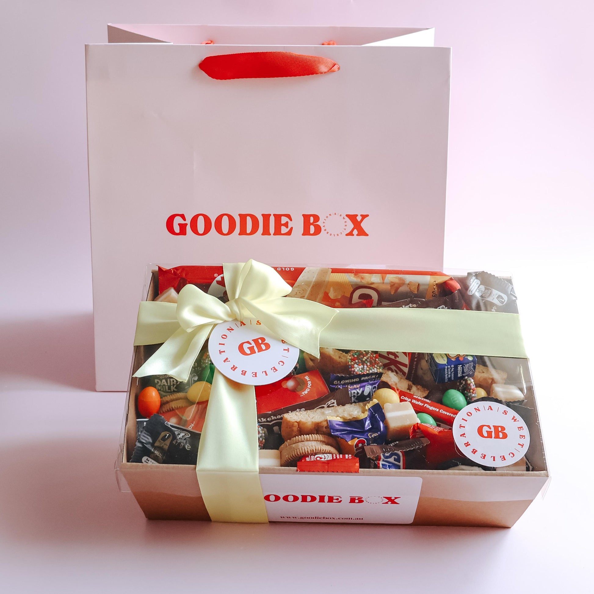 Gooddie Box chocolate lovers dessert box gift wrapped with cream ribbon and Goodie Box gift bag on pink background Perth same day delivery