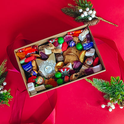 Box of assorted candies on a red background with Christmas decorations