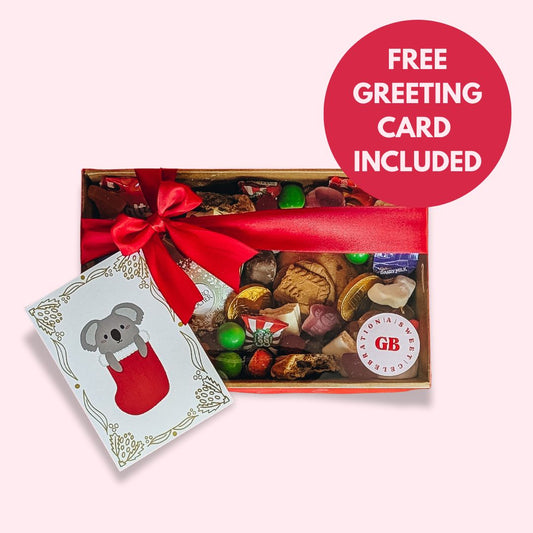 Box of assorted chocolates with a red bow and a free greeting card on a light pink background.