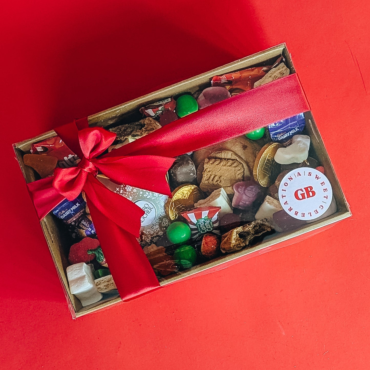 Box of assorted chocolates with a red ribbon on a red background