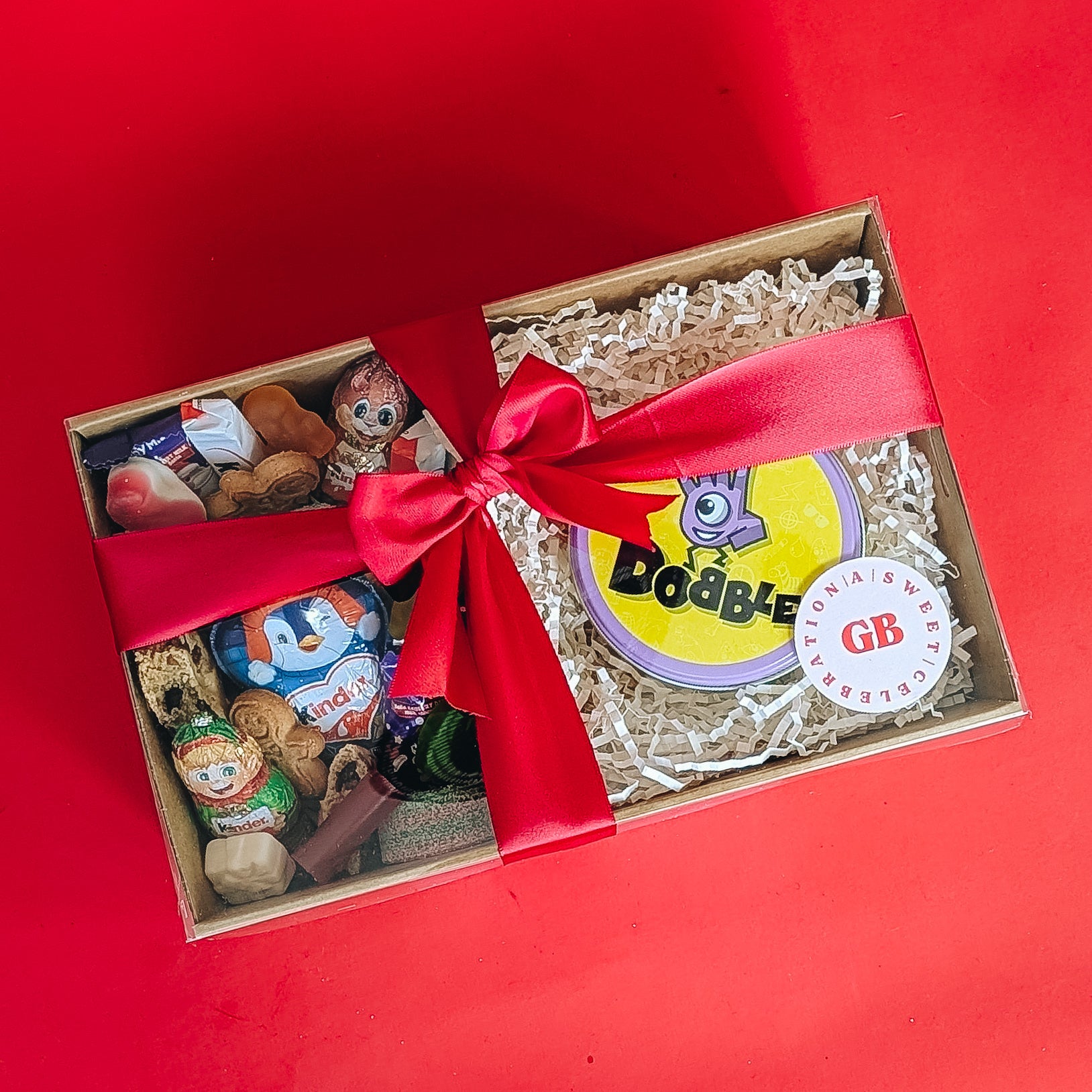 Gift box with toys and a red ribbon on a red background