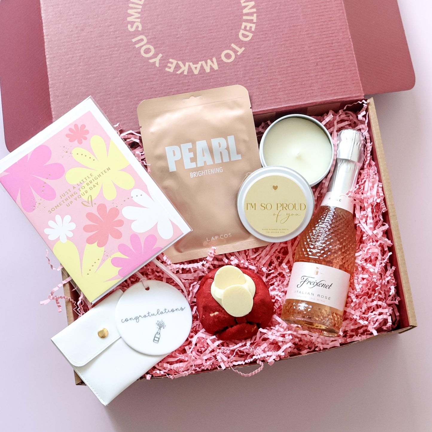 Congratulations gift box open showing sparkling rosé, Lapcos face mask, candle, cookie and keepsake tag