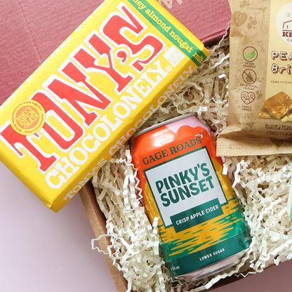 Congratulations gift for him close up of Tony's Chocolonely honey almond nougat and Gage Roads Pinky's Sunset apple cider with Kelly's Peanut Brittle