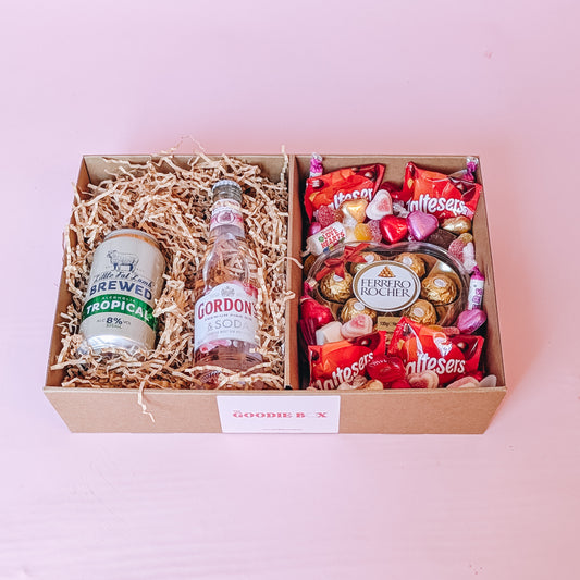 photograph of valenitne's romantic gift hamper. It includes a can of cider, a pink gin, and an assortment of chocolates and lollies including: a ferrero Rocher heart, maltesers, swizzels love hearts and love themed sweets.