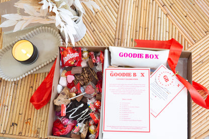 Goodie box with snacks and a candle on a woven surface