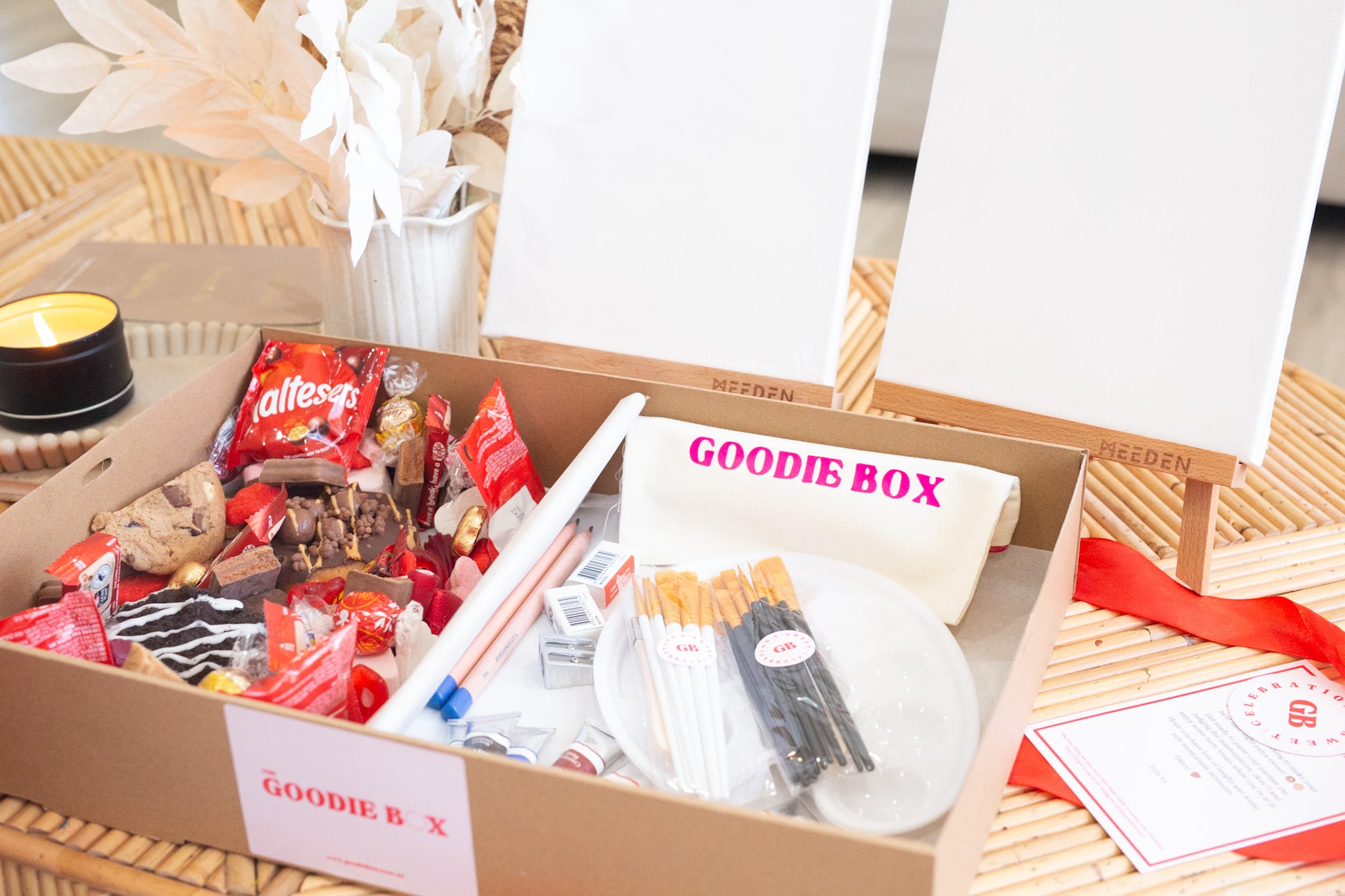 Goodie box with snacks and stationery items on a wooden surface.