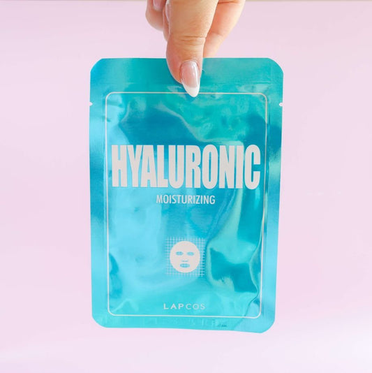 Hyaluronic moisturizing face mask packaging held by a hand on a light pink background