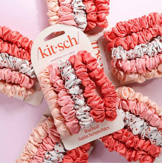 Kit-sch ruched satin scrunchies in pink and white on a pink background