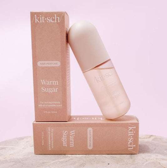 Kit-sch Warm Sugar hair perfume bottle and packaging on a light pink background