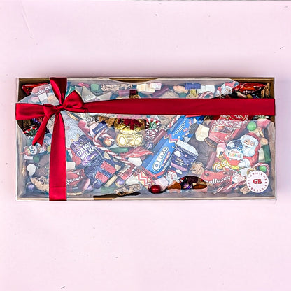 Assorted candy box with a red ribbon on a light pink background