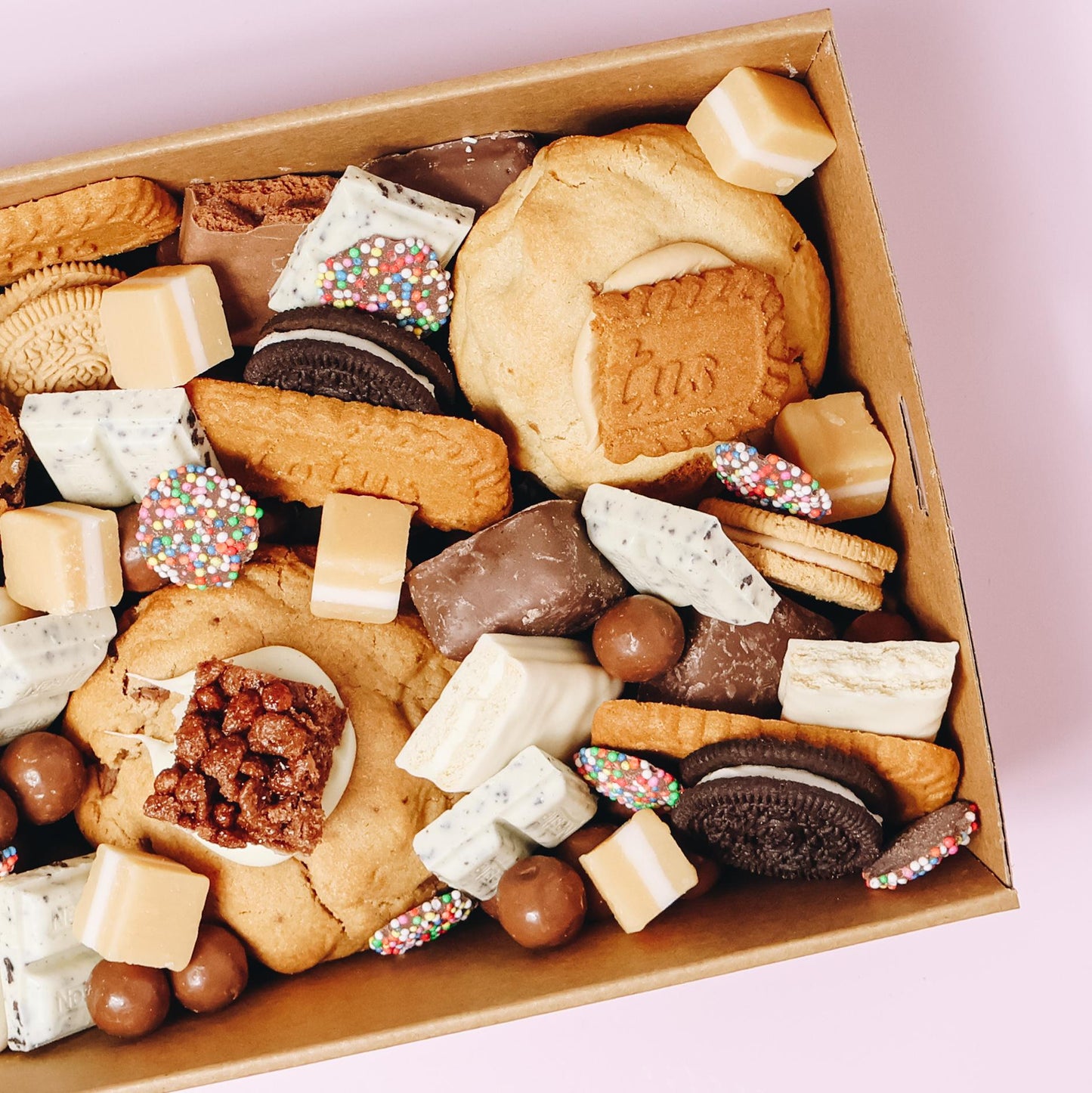 Angled overhead view of loaded cookies gift box with Biscoff, Oreo, fudge pieces and rainbow freckles