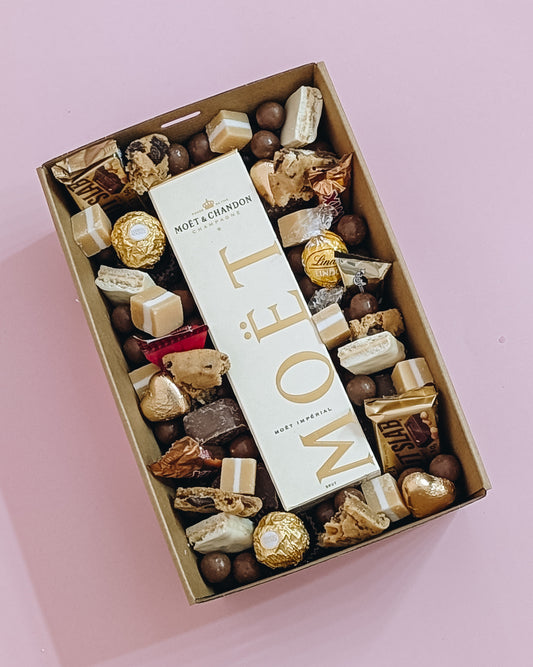 Photograph of Luxury Moët Champagne and chocolate gift hamper with personalized message. Wrapped with a beautiful gold bow ready for gifting. 