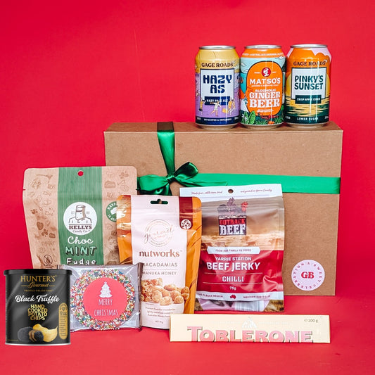 gift hamper with beer, cider and ginger beer with chocolates, beef jerky, crisps and nuts on a red background.