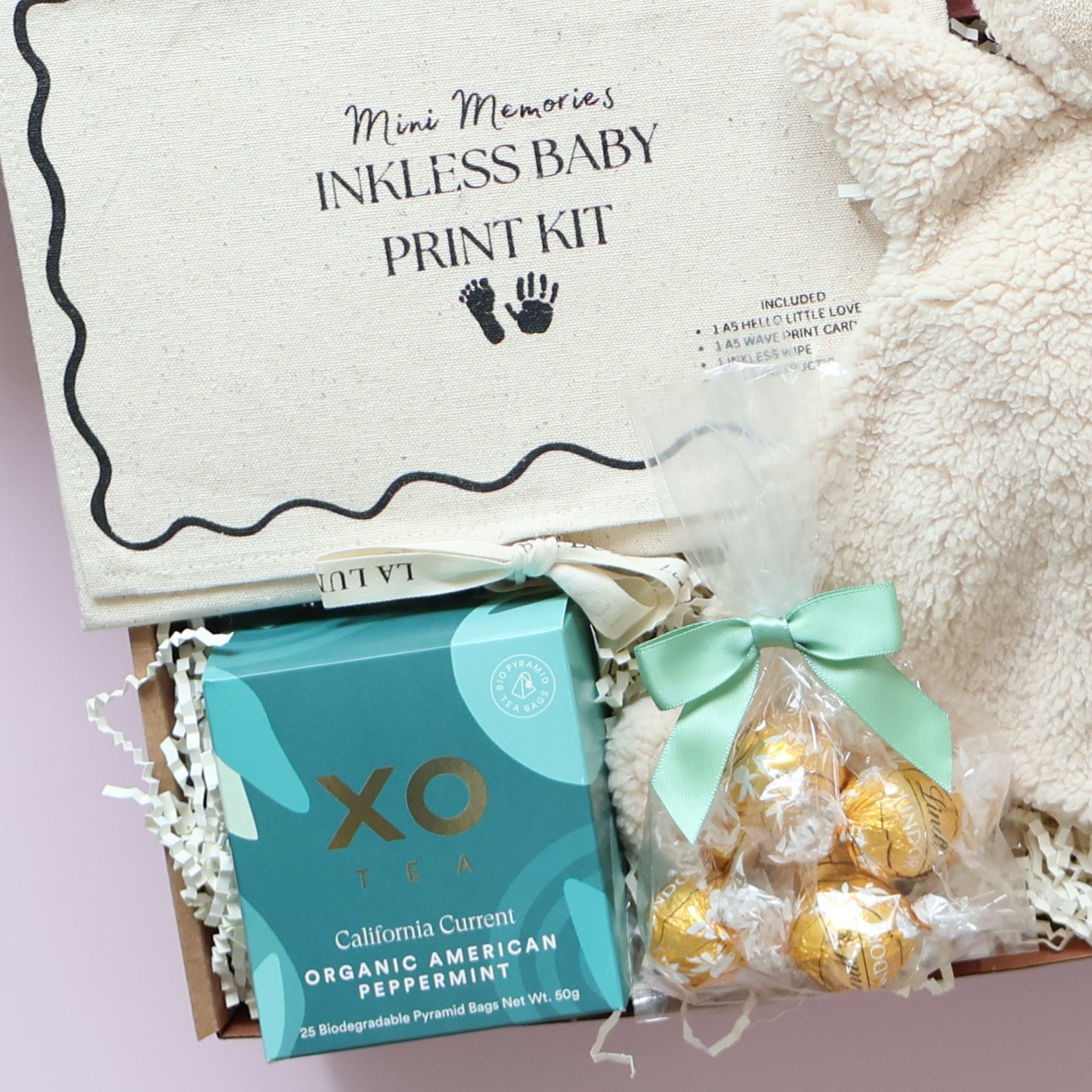 New baby gift box contents featuring XO Tea, Lindt chocolates and inkless baby print kit