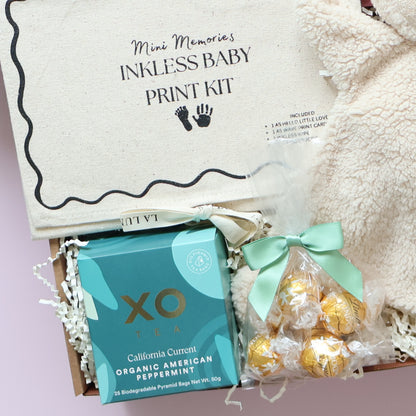 New baby gift box contents featuring XO Tea, Lindt chocolates and inkless baby print kit
