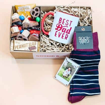 Fathers Day gift hamper with snacks, mug,  magnetic photo with frame and socks on a light background
